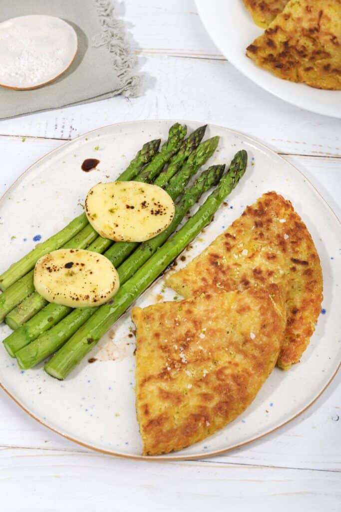 Two slices of potato rosti, 5 asparagus stalks and two pieces of mozzarella on a plate, with dressing | Hurry The Food Up