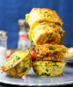 A pile of four breakfast egg muffins, on a grey plate, some condiments visible in the background. | Hurry The Food Up
