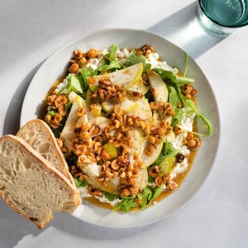 Bird's-eye view of cottage cheese salad and two pieces of bread served on a white plate which is on a light surface. Next to it, there is a glass of water | Hurry The Food Up
