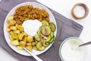 The dish with cucumber salad are on the table on a plate with fork, towel, salt and sauce #potatoes #tomato paste | hurrythefoodup.com