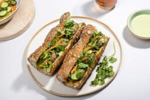 Two lentil banh mi on a plate, a small bowl of sauce accompanying them | Hurry The Food Up