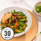 Lentils with Vegetables in Tahini Sauce are served in the white plate that stands on the beige plate that is on the table. Next to it there is a plate with chopped parsley and olive oil | Hurry The Food Up